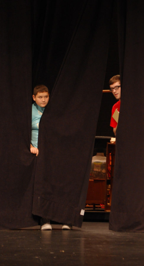 Sophomore Jessey Perkins and Freshman Chase Meehan hide in the curtain for a scene in the play.