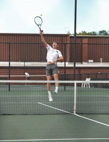 Senior Isaac Cornett-McBride jumps to hit tennis ball.