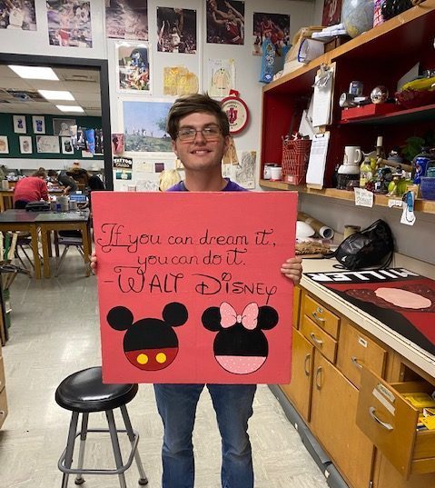 Senior Dawson Poe poses with his painted ceiling tile, which features Micky and Minnie Mouse.