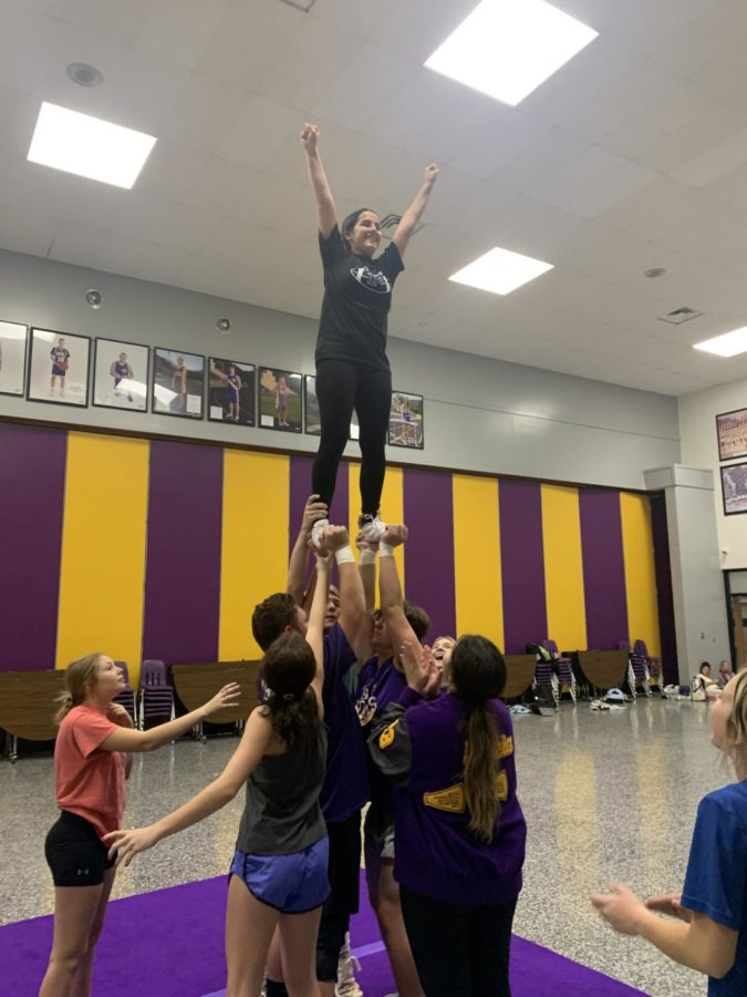 Junior Elena Carmona is lifted into the air by the male cheerleaders.