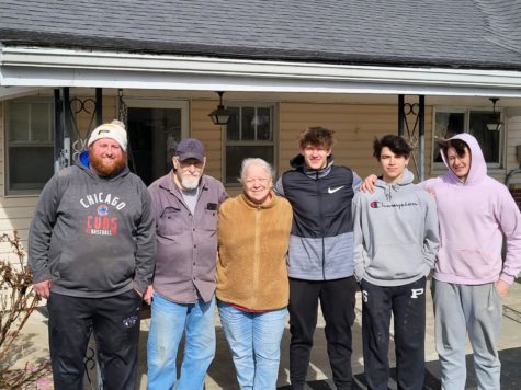 Head Coach Neil Dittmer and sophomore Garrett Hickman and freshmen Trey Minton and Wyatt Baker pose with a family they helped in the community.