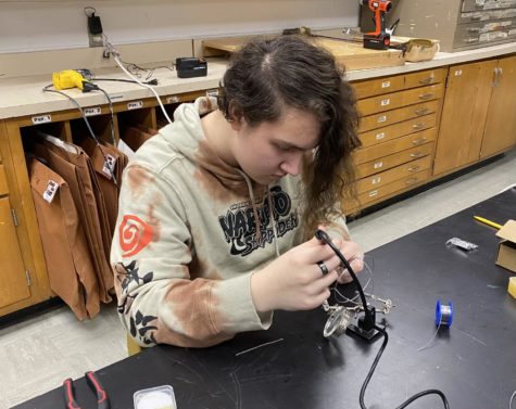 Junior Dyson Nichols solders is art piece during class. 