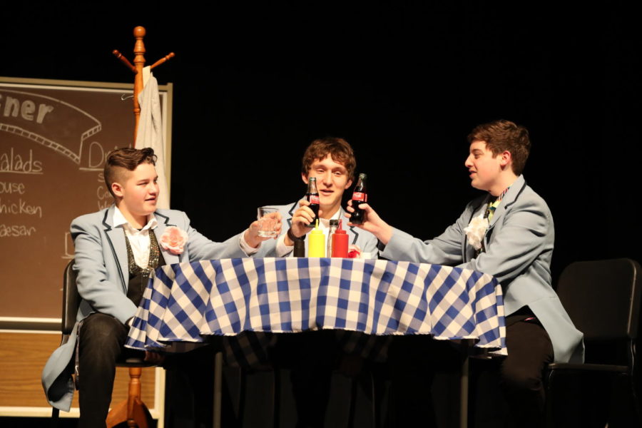 Eighth grader Wylee Ruckman, senior AJ Lopez and freshman Cannon Lambdin chat at a dinner table during the “Life is Like a Double Cheeseburger” play in February.
