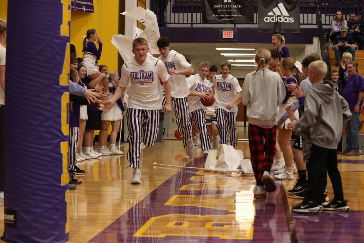 The Varsity Boys Basketball team run through the banner.