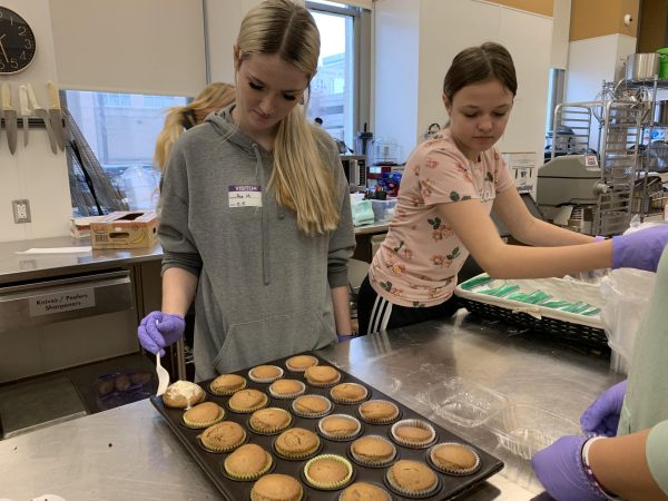 Freshmen Ava Middleton and Sophie Holliday work to ice muffins.