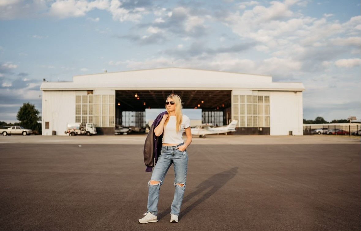 Senior Faith Gammon poses in front of an airport hanger.