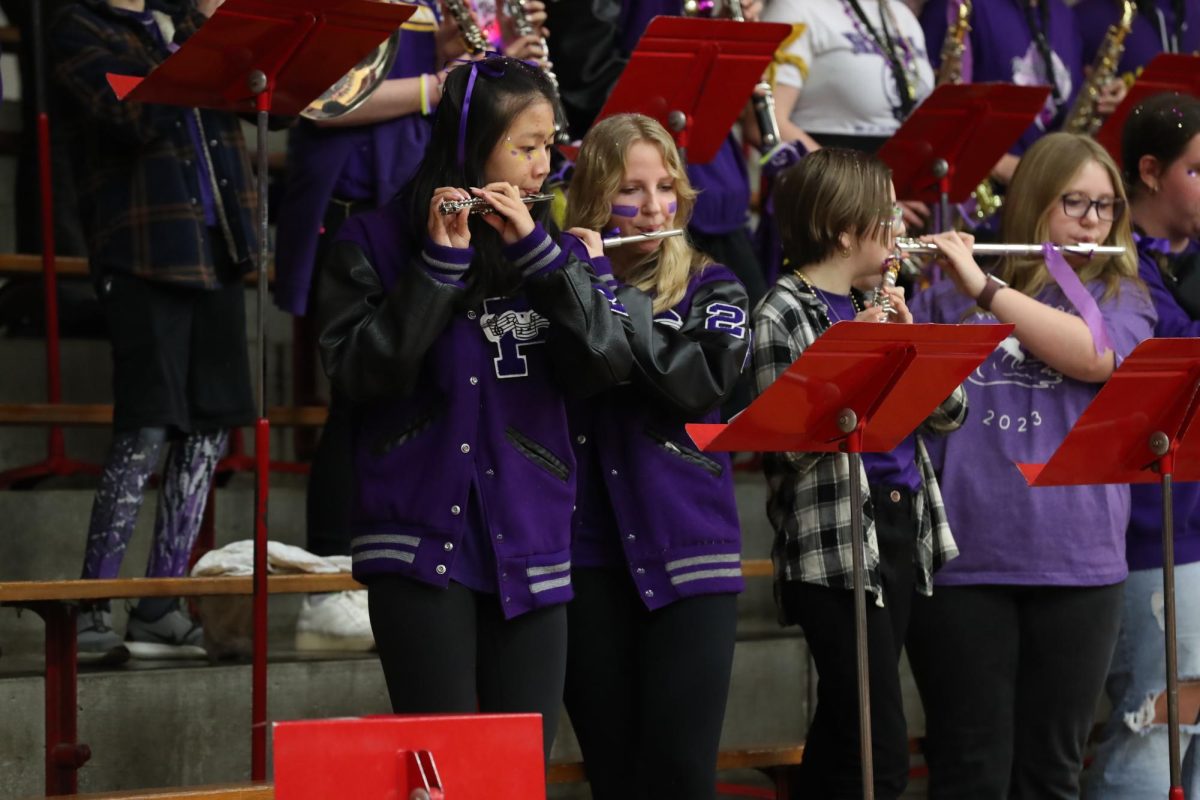Seniors Lina Zheng and Trinity Thompson play their flutes together.