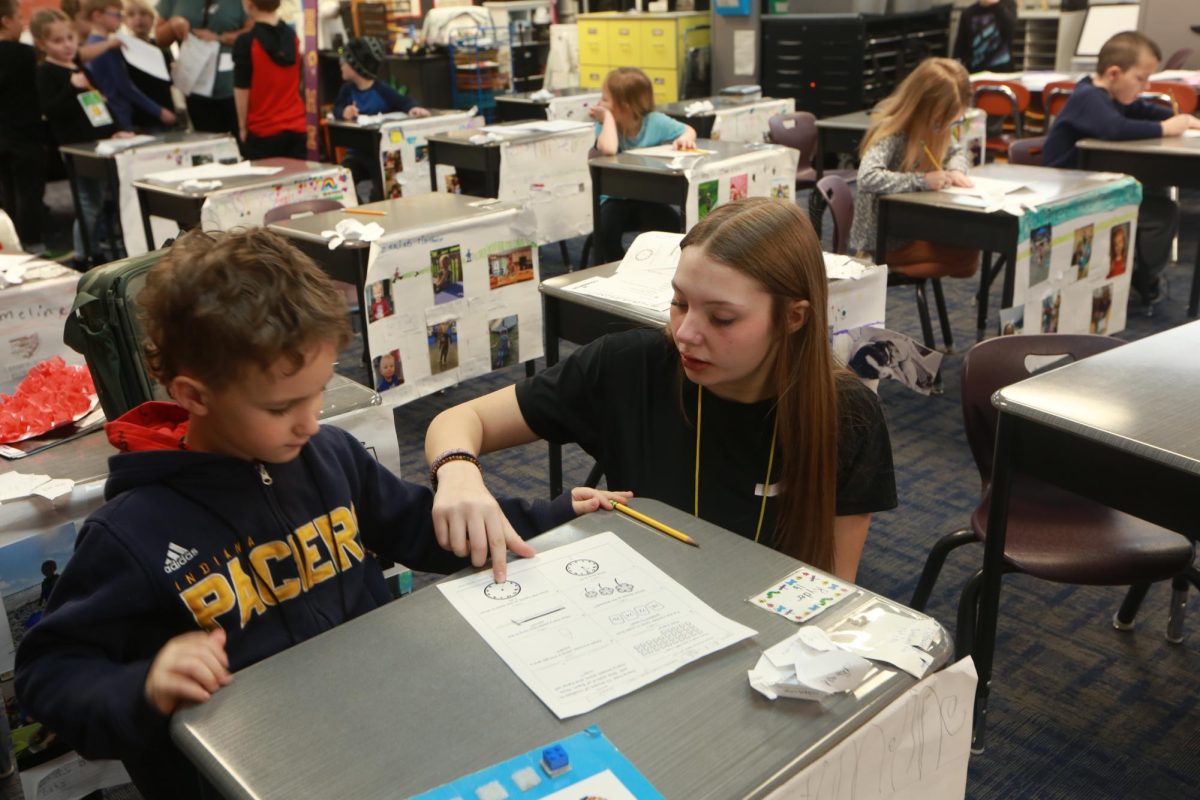 Senior Harleigh Poe helps an elementary student with his work.