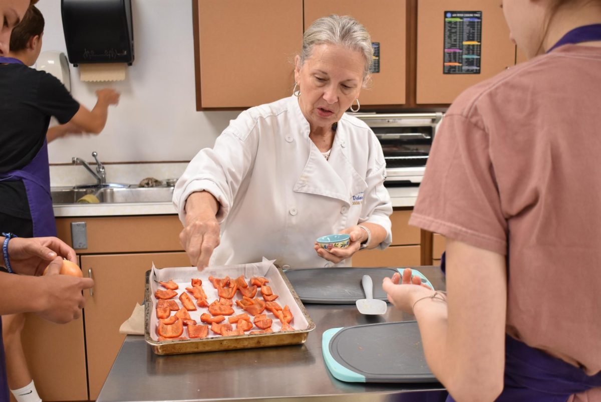 Teacher Debbie Andry, sprinkles salt on the peppers.