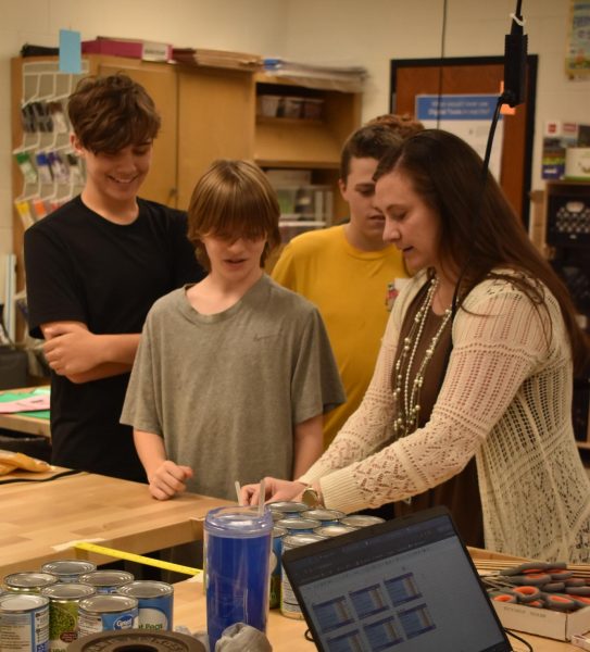 Stem teacher Lori Stroud helps students set up there bridge. 