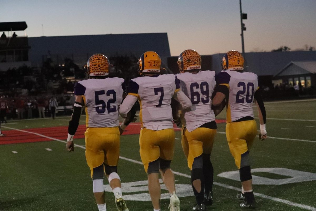 Seniors walk to the middle of the field for the coin toss.