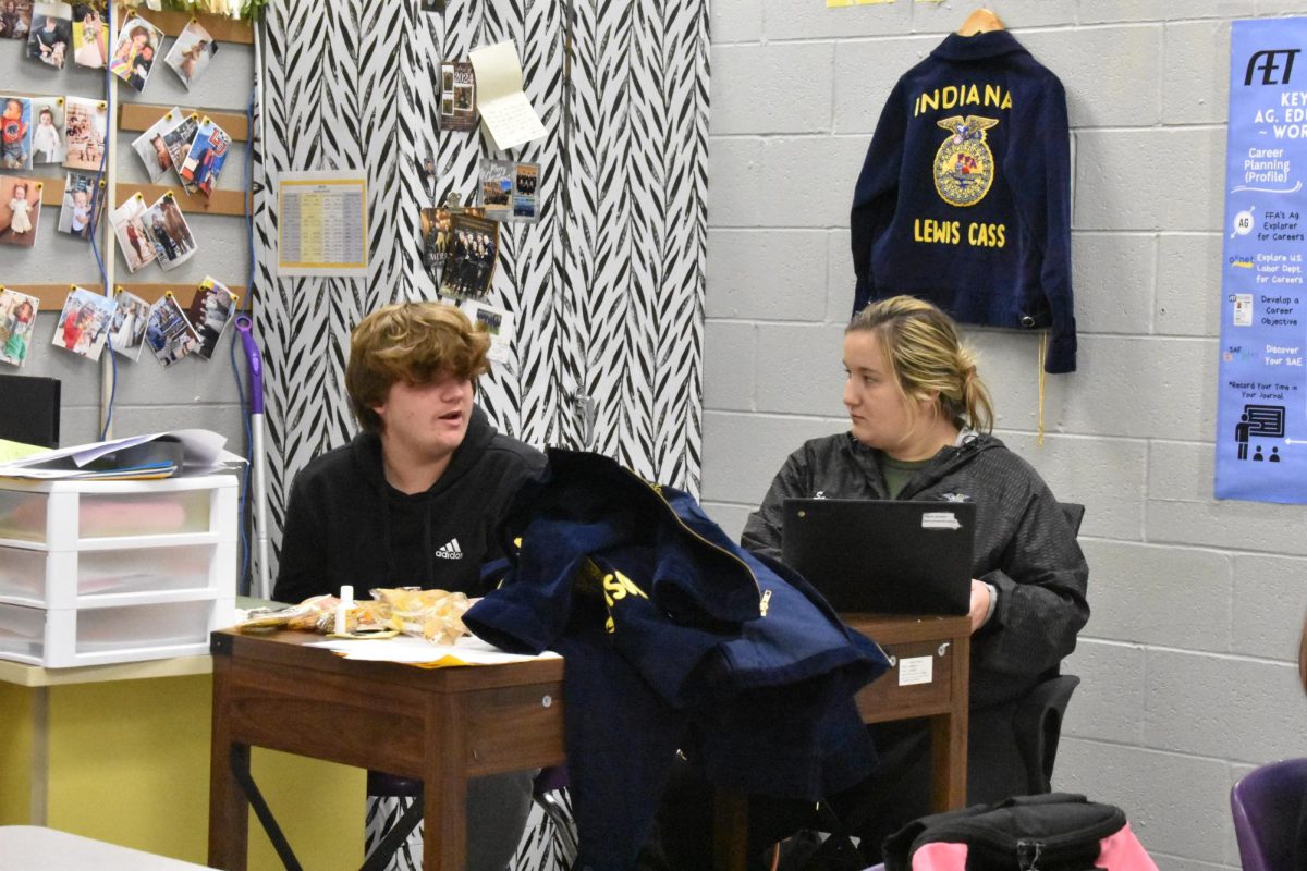 FFA Advisor Samantha Goen, is helping FFA Officer Graydan Paggett.