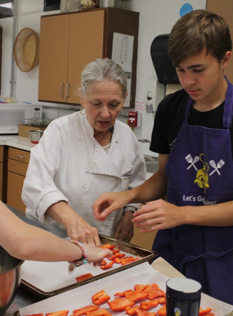 Sophomore Marcus Longest getting assistance by culinary Debbie Andry.