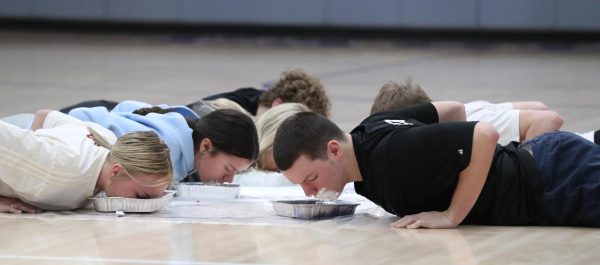 Underclassman homecoming court searches for two M&M's in a pan of whipped cream.