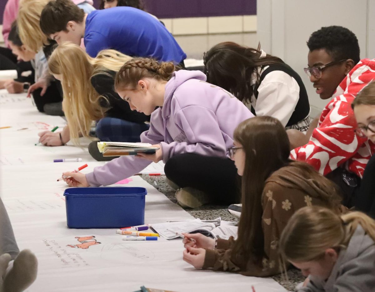 Freshman Bailey Tyler writing on the poster.
