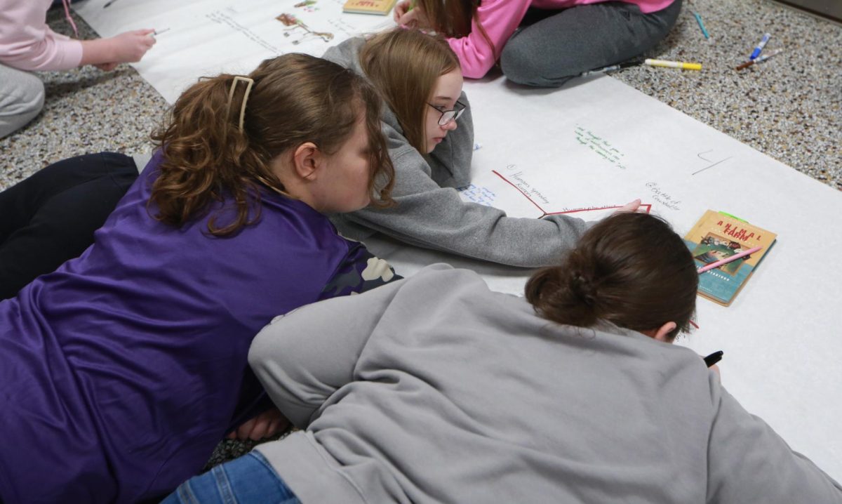 Freshman Karma Ledgerwood, Emily Lindsey, Alyssa Jones draw on the poster.