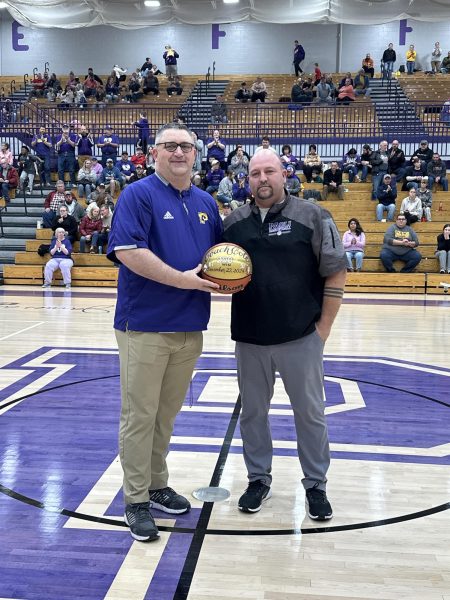 Cole poses with athletic director Darek Newkirk with a painted ball honoring his 200th win