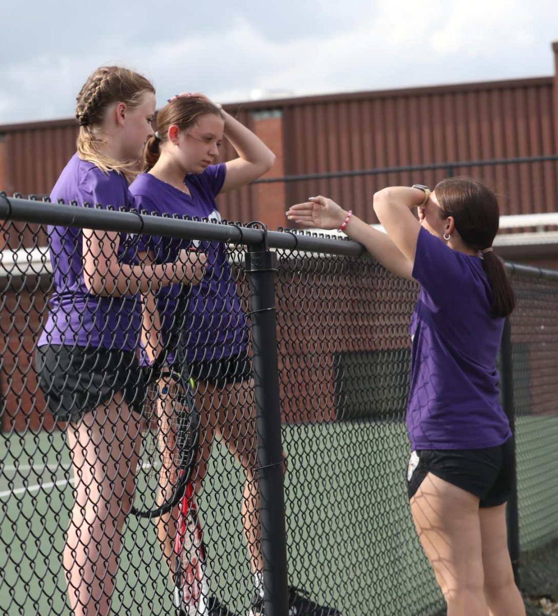 Coach Gracie Brown talks to eighth grader Audrey Crowder and seventh grader Tilly Asbell.