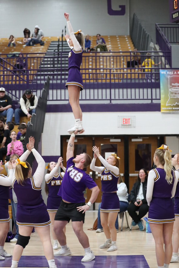 Senior Coy Busick holds senior Julie Magner in a one-handed lib on the sidelines of a Rams basketball game. 