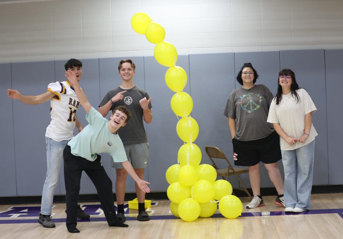Junior Alvaro Gavina, Senior Jaxton Deaton, Junior Garrett Cook, and Seniors Necia Owens and Alivia Sweet pose with the balloon tower they built during a JAG activity.