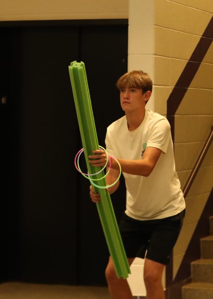 Freshman Tripp Spencer attempts to catch rings on a pool noodle.
