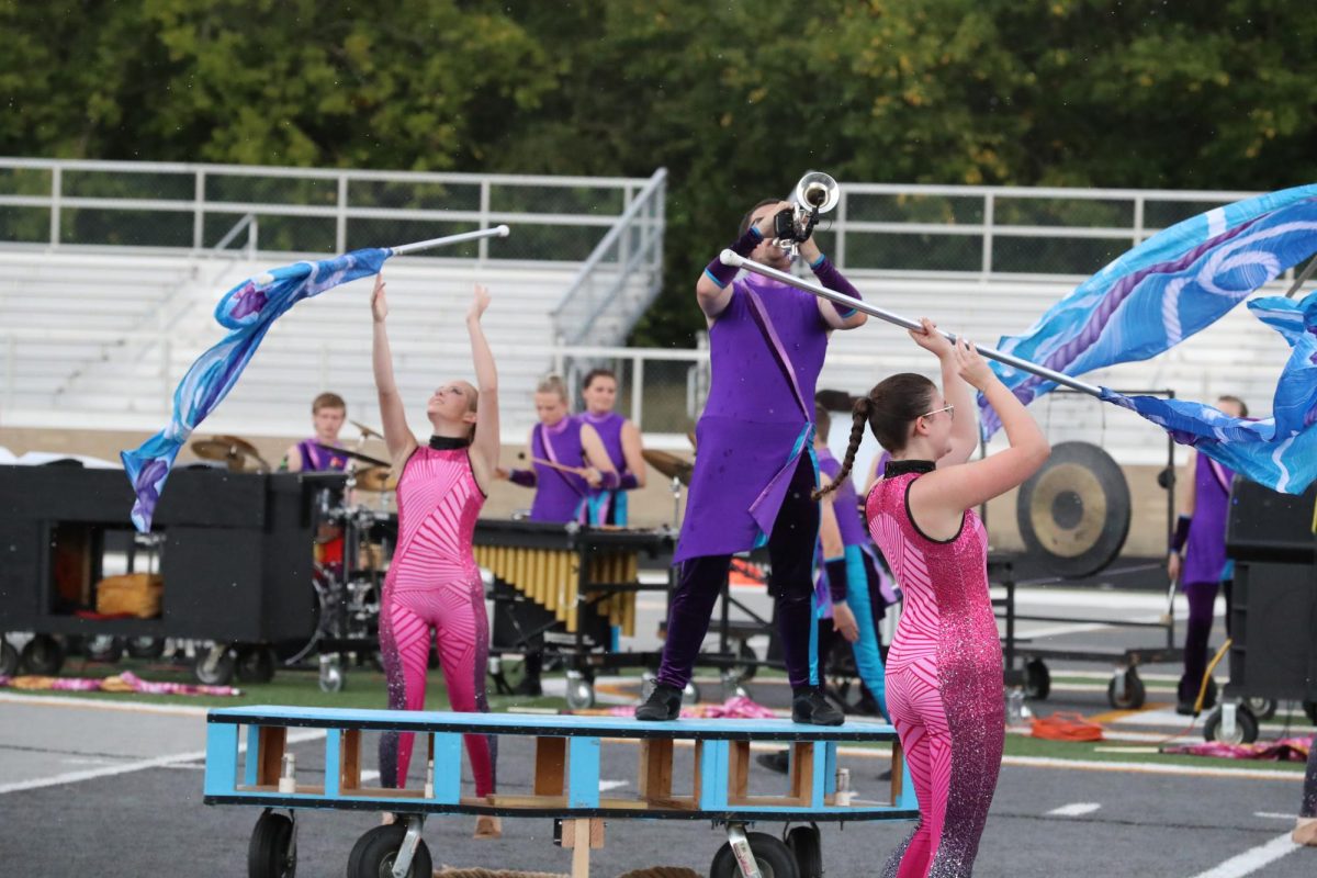 Senior Nathaniel Dixon performs one of his solos with color guard members, with sophomore Brooke Goller and junior Ella Grunden performing around him.