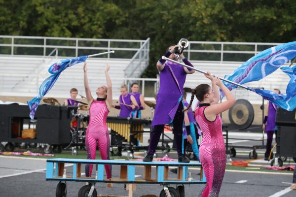 Senior Nathaniel Dixon performs one of his solos with color guard members, with sophomore Brooke Goller and junior Ella Grunden performing around him.