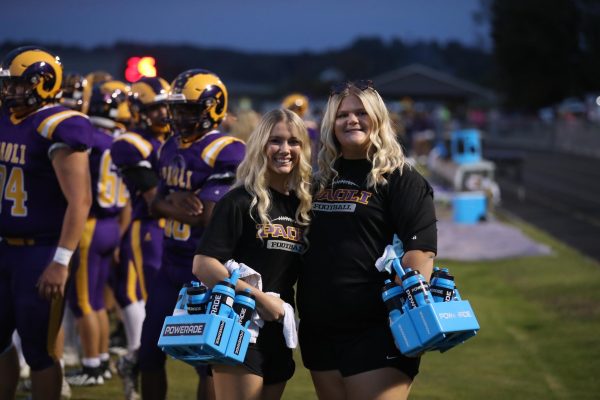 Maddie Vernon and Libby Newkirk pose together on the football sidelines.