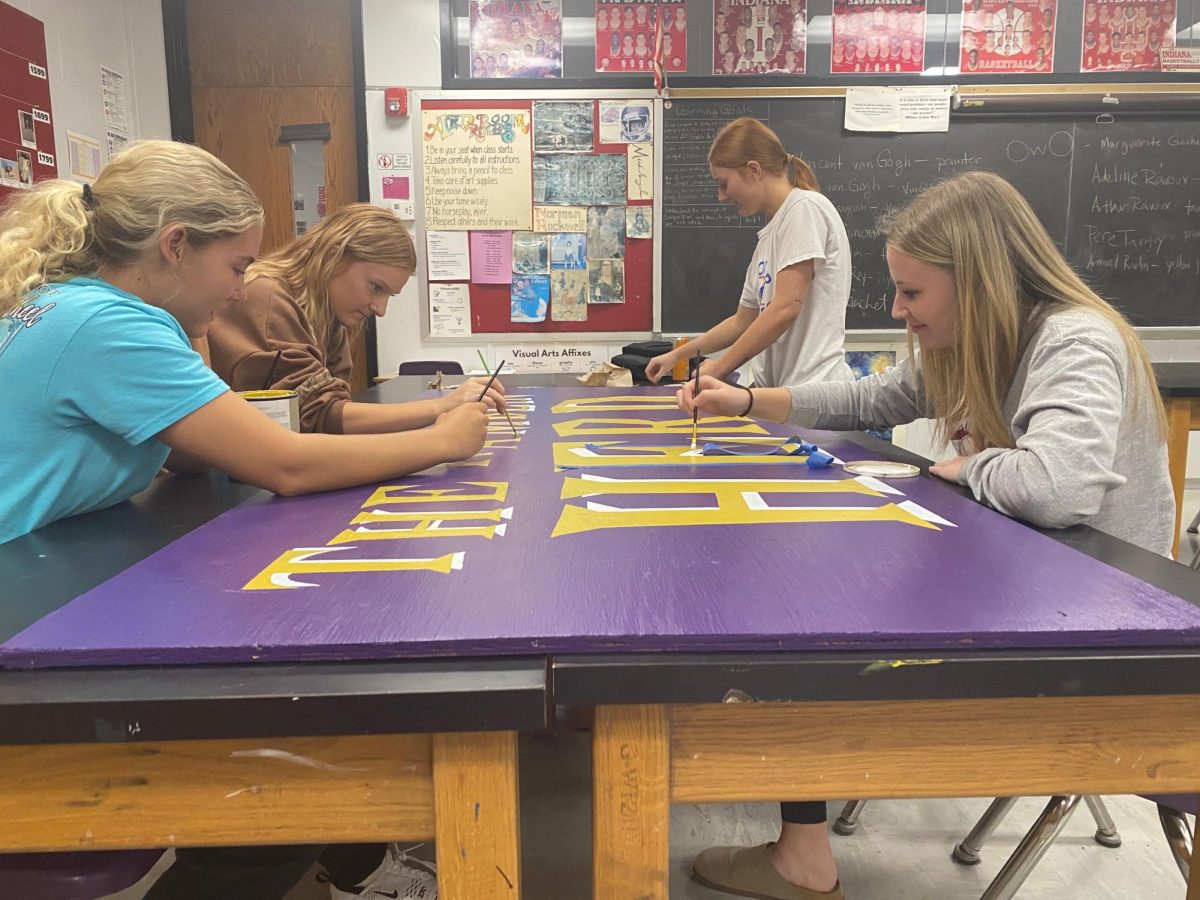 Seniors Maddie Vernon, Ava Hall, Audrey Hall, and Abby Poe work on the Ram Herd sign for the football field.