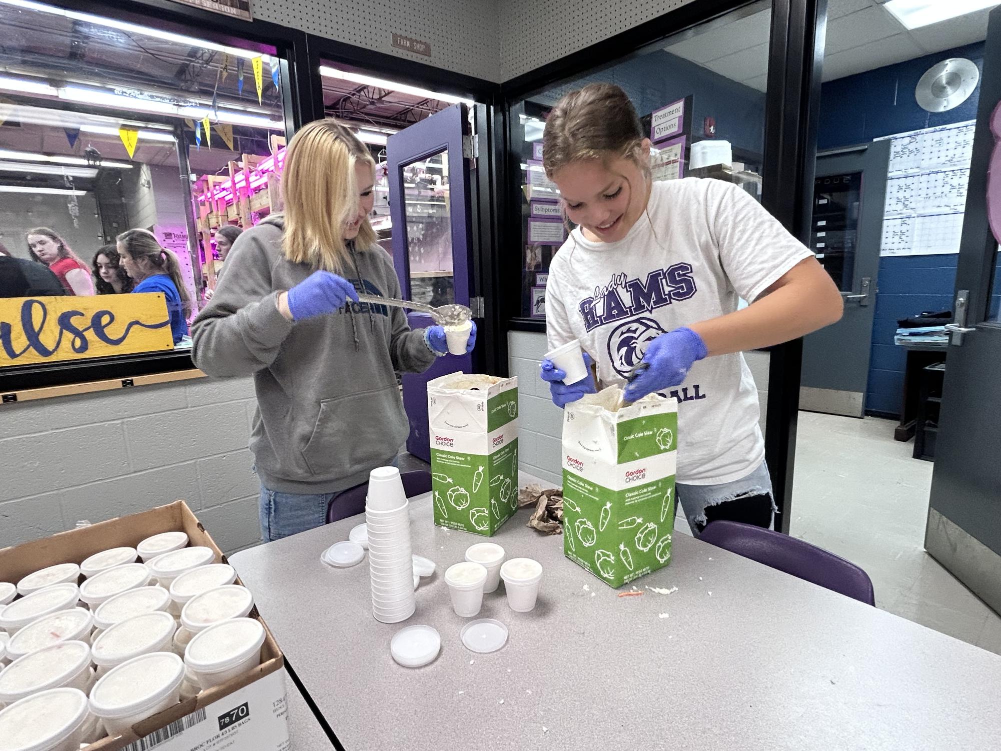 Seniors Alissa Henry and Cherokee Hopper package meals for the FFA project.