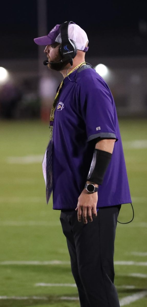 Neil Dittmer stands on the sidelines watching his players run the ball down the field. 
