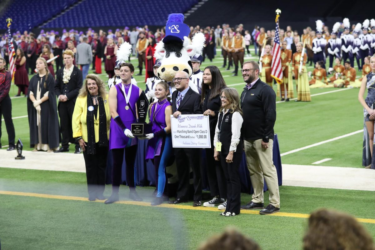 Drum Majors Cannon Lambdin and Vanessa Thacker pose with Band Director Christian Karkosky after winning the State title. Also pictured in the photo is the President of ISSMA, representatives from Prairie Farms, the 2024 ISSMA Scholarship winner, and Buttercup.