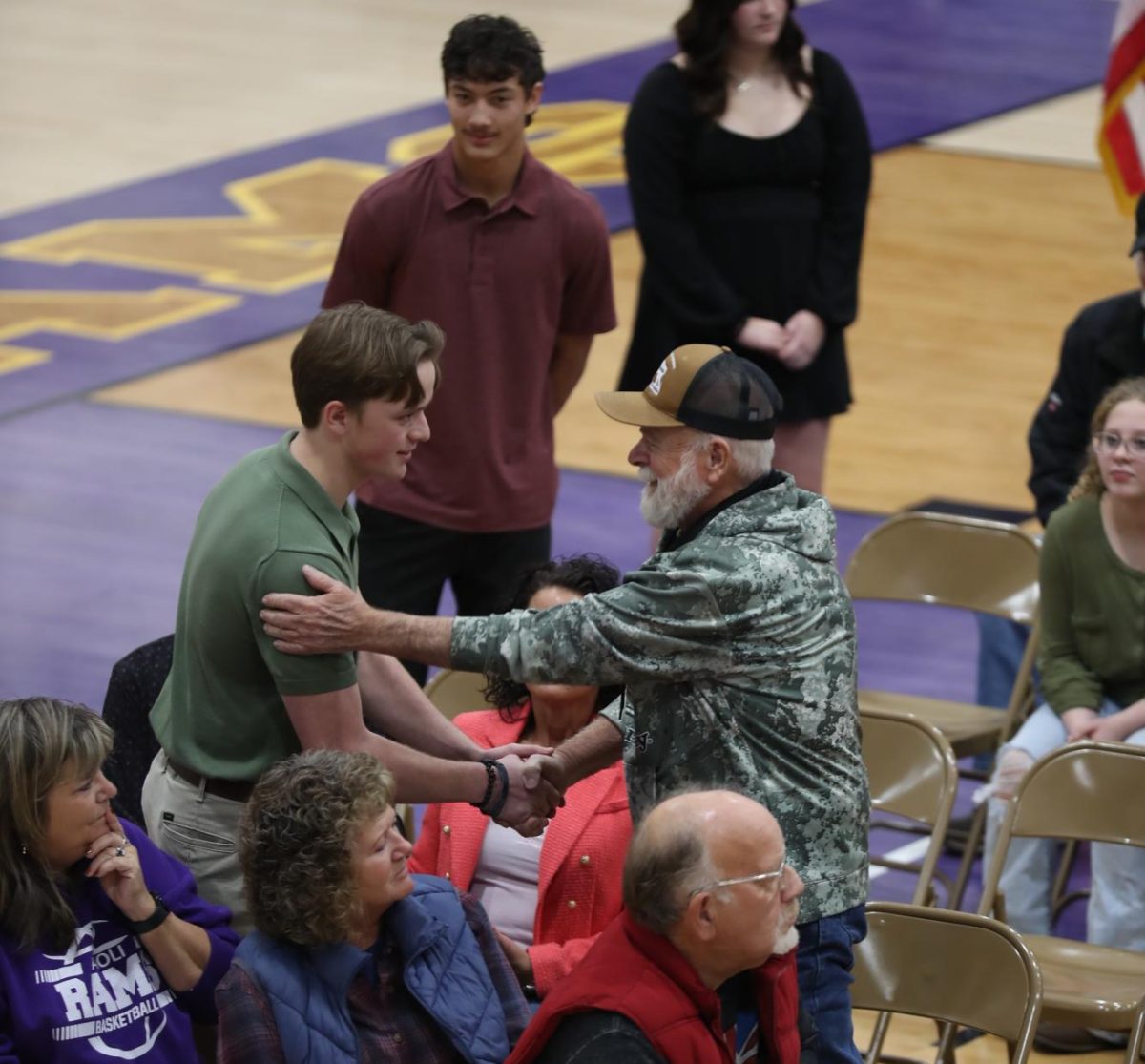 Junior Garrett Cook shakes hands with his grandfather, Charles Bob Radcliff.