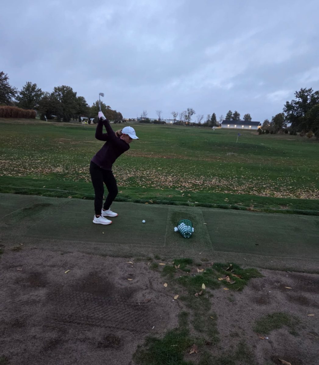 Camley Whitfield swings her golf club to hit a golf ball during practice.