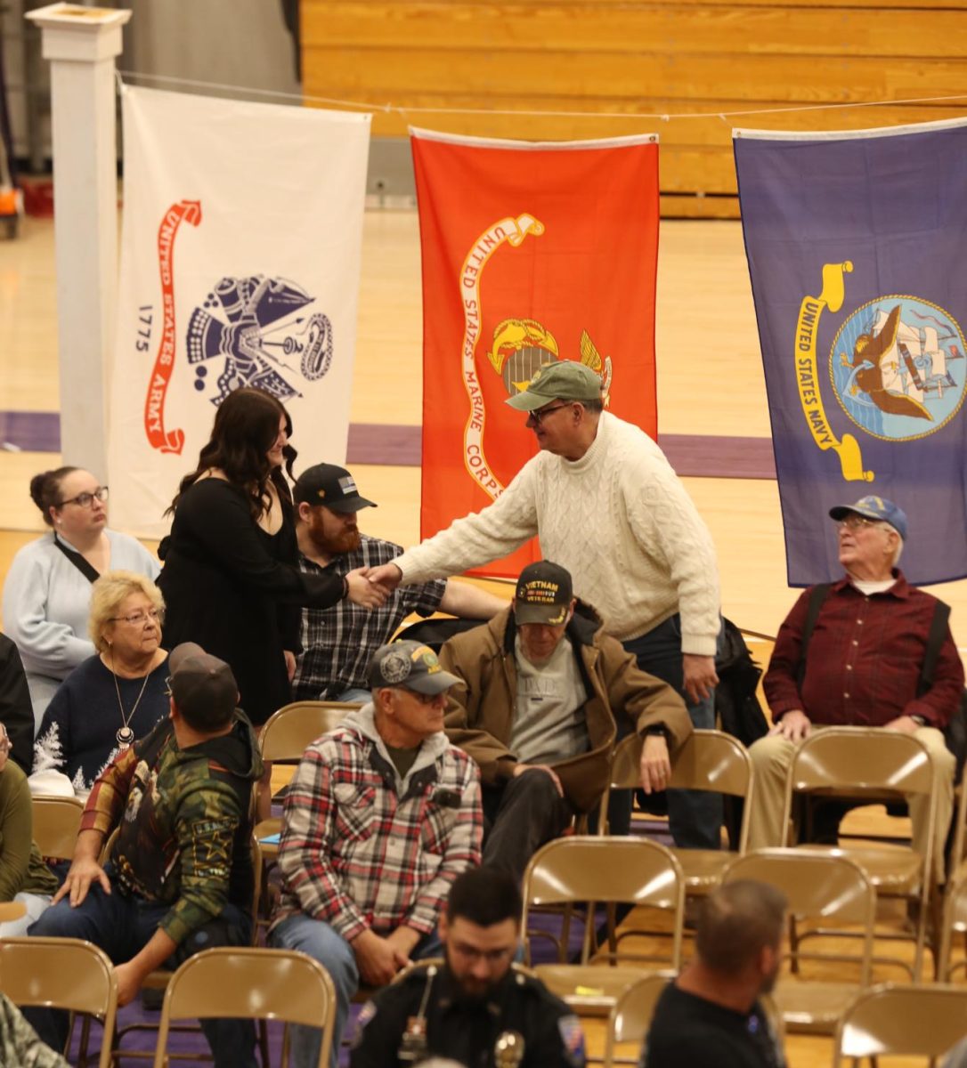 Junior Allison Livingston shakes a veteran's hand during the Veterans Day program.