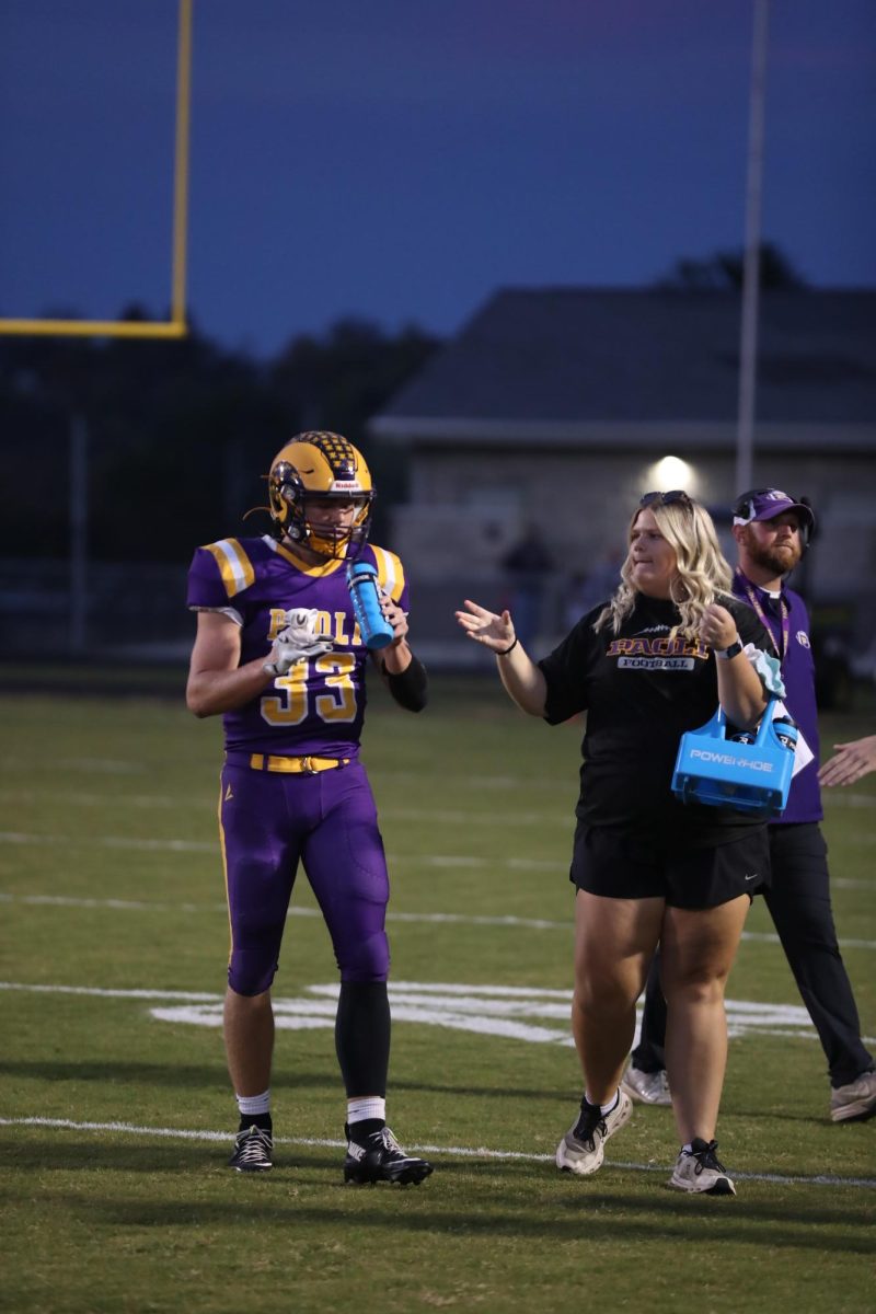 Senior Libby Newkirk hands off water to a Ram during a game.